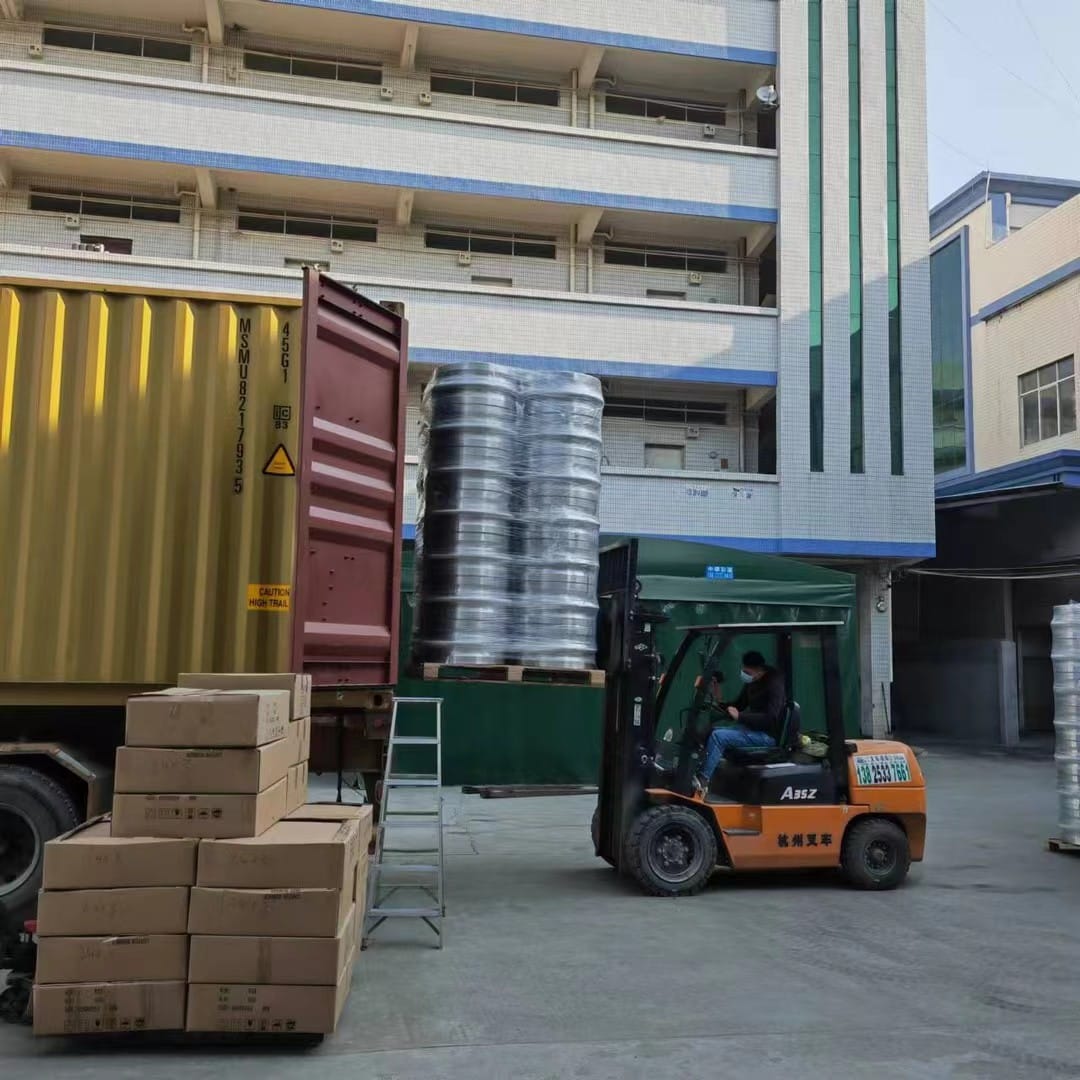 Forklift moving cartons near an export container at an alloy wheel factory