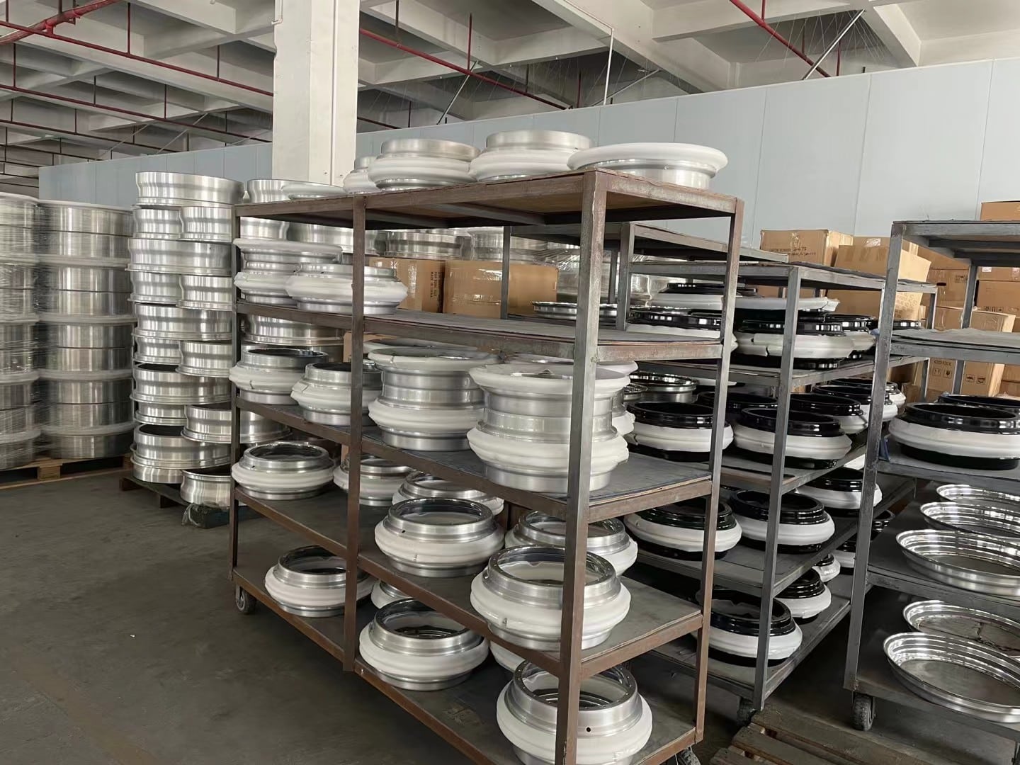 Finished alloy wheels organized on metal racks before packing