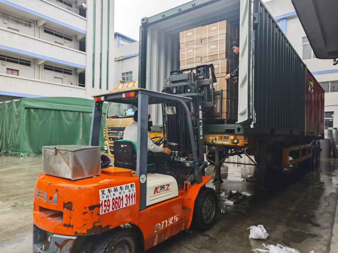 Forklift moving alloy wheel cartons near a truck in the factory yard